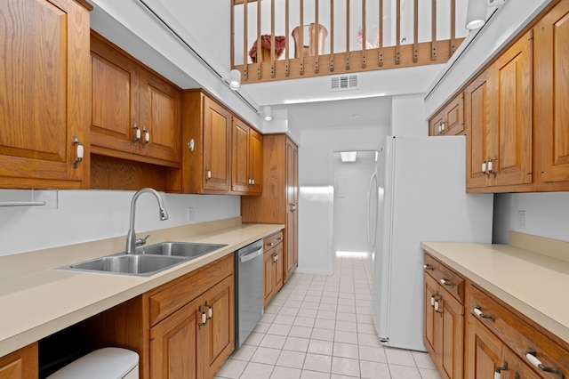 kitchen with brown cabinetry, visible vents, dishwasher, and a sink