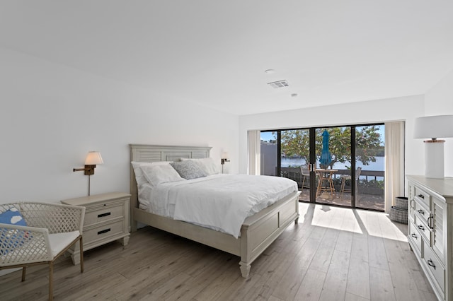 bedroom with access to outside, light wood finished floors, and visible vents