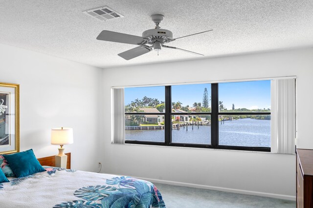 bedroom featuring a textured ceiling, ceiling fan, carpet flooring, and visible vents