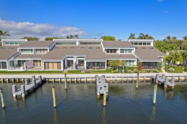 rear view of property with a water view, a sunroom, and uncovered parking