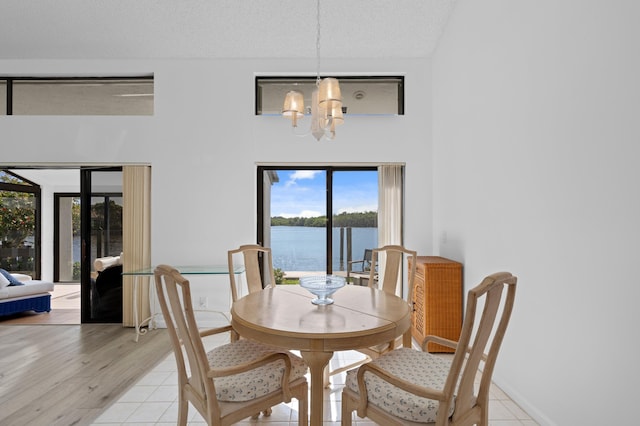 dining room with a chandelier, a water view, and a textured ceiling