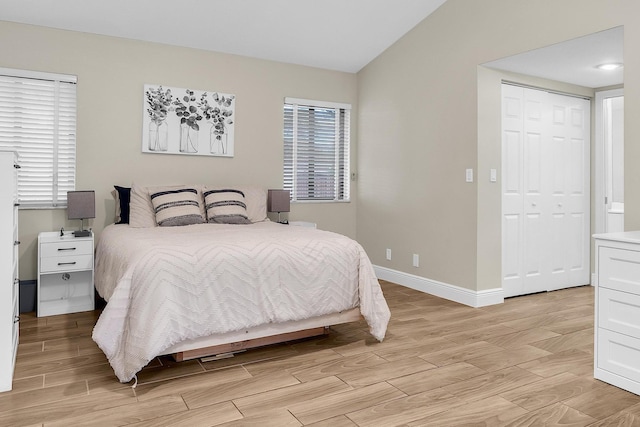 bedroom featuring vaulted ceiling, light wood finished floors, a closet, and baseboards