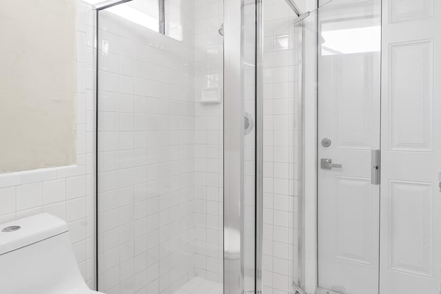 full bath featuring toilet, a stall shower, and tile walls