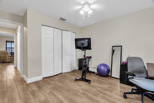 exercise room with wood finish floors, visible vents, ceiling fan, and baseboards