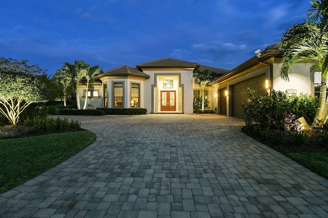 view of front of house featuring an attached garage, decorative driveway, and stucco siding