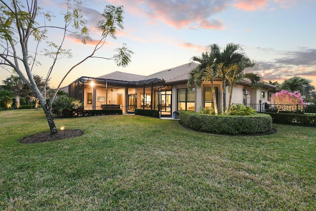 rear view of property featuring stucco siding, a ceiling fan, and a yard