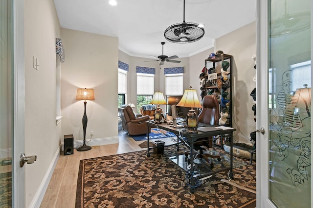 office space with baseboards, ornamental molding, ceiling fan, and wood finished floors