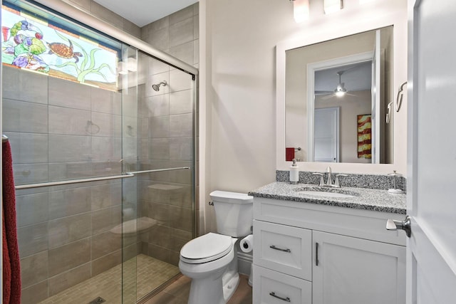 full bath with ceiling fan, vanity, a shower stall, and toilet