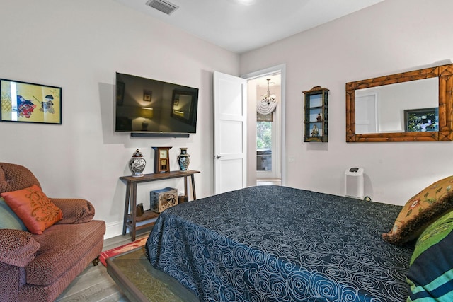 bedroom featuring a notable chandelier, visible vents, and wood finished floors