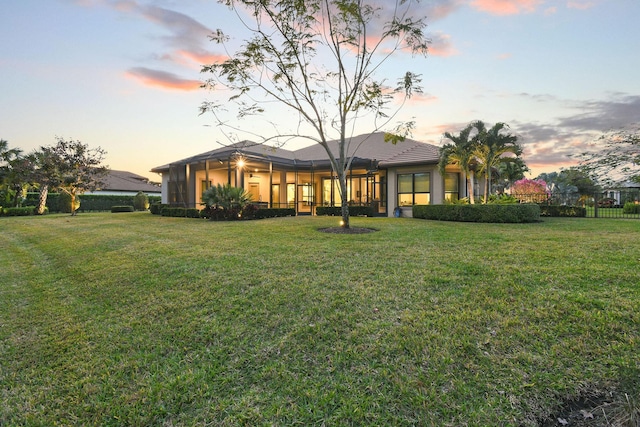 rear view of house featuring fence and a lawn