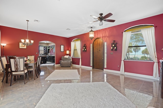 foyer entrance with arched walkways, ceiling fan with notable chandelier, visible vents, baseboards, and marble finish floor