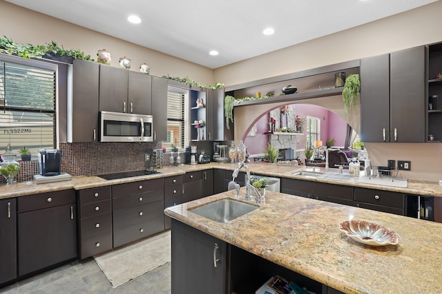 kitchen featuring open shelves, stainless steel microwave, backsplash, a sink, and black electric cooktop