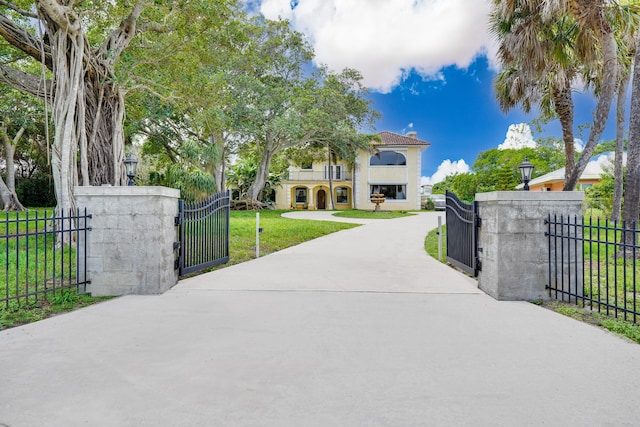 view of front of property with a fenced front yard, stucco siding, a front yard, a gate, and a balcony