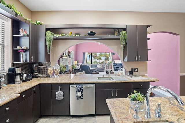 kitchen featuring dishwasher, open shelves, a sink, and light stone countertops