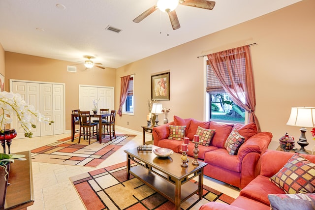 living room with a ceiling fan, visible vents, and baseboards