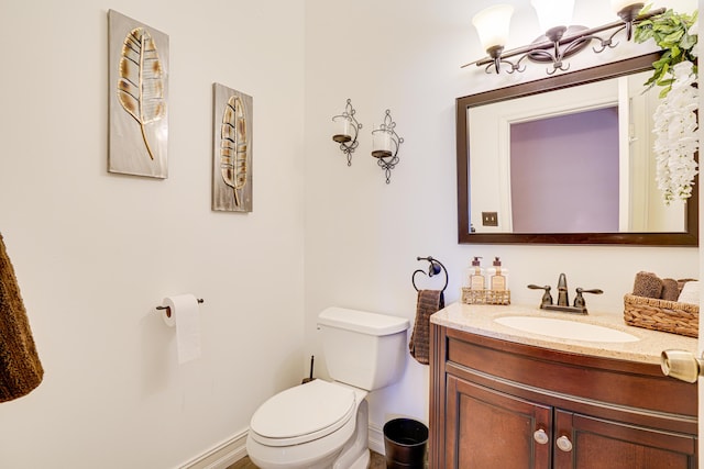 half bathroom with toilet, baseboards, and vanity