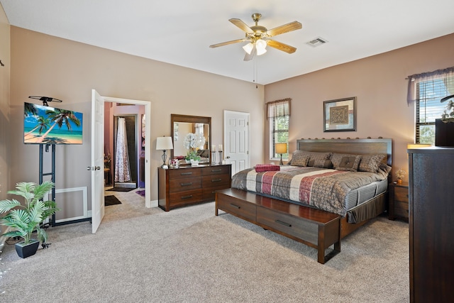 carpeted bedroom featuring baseboards, multiple windows, visible vents, and a ceiling fan