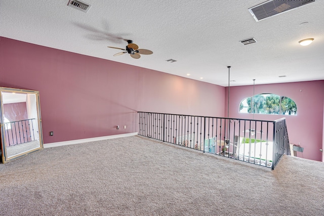 carpeted empty room with visible vents, a textured ceiling, and baseboards