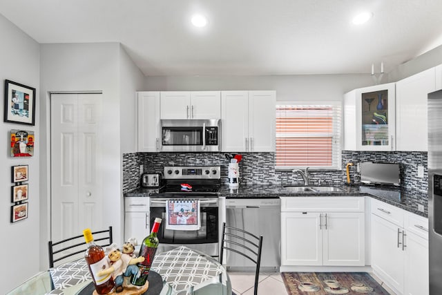 kitchen with appliances with stainless steel finishes, a sink, white cabinetry, and decorative backsplash