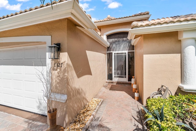 doorway to property featuring a garage and stucco siding