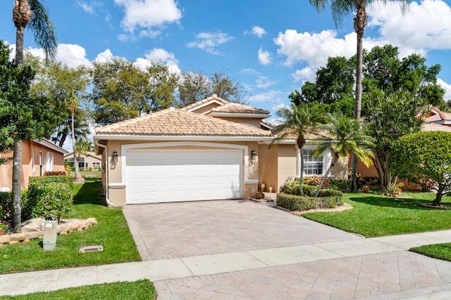 view of front of home featuring decorative driveway, stucco siding, an attached garage, a tiled roof, and a front lawn