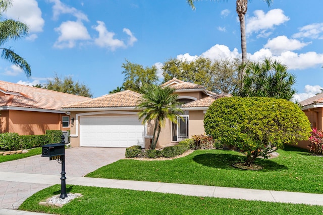 view of front of home with a garage, a front yard, decorative driveway, and stucco siding