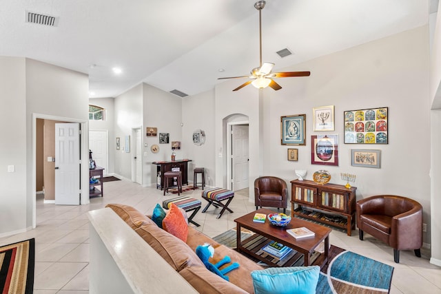 living area featuring light tile patterned floors, high vaulted ceiling, arched walkways, and visible vents