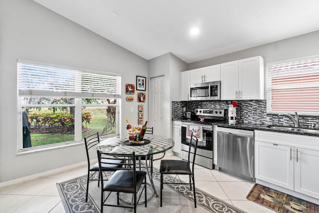 kitchen featuring light tile patterned floors, tasteful backsplash, stainless steel appliances, white cabinetry, and a sink