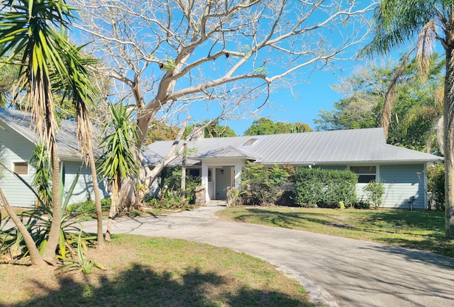 view of front of home featuring metal roof, driveway, and a front lawn