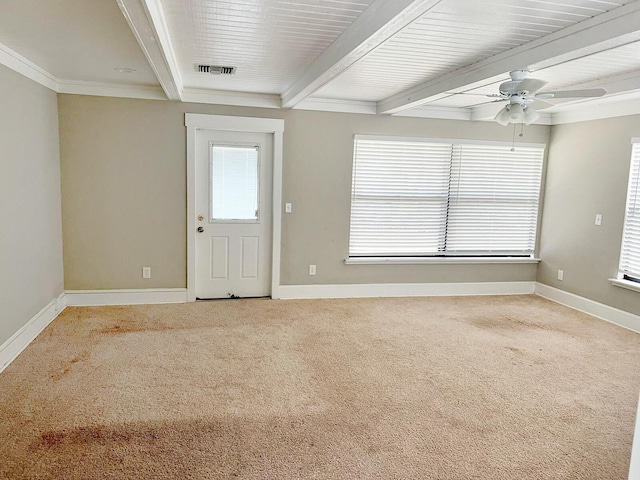 spare room with a wealth of natural light, beam ceiling, carpet flooring, and visible vents