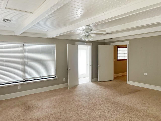 empty room with baseboards, visible vents, ceiling fan, beamed ceiling, and carpet