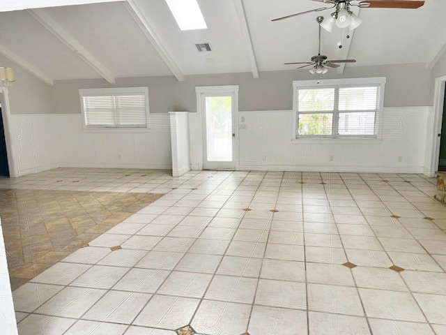 interior space with a wainscoted wall, vaulted ceiling with beams, light tile patterned floors, visible vents, and a ceiling fan