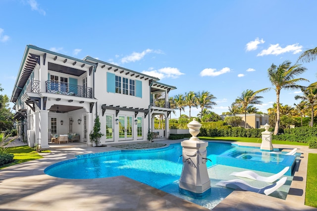 back of property with a patio, a balcony, french doors, an outdoor pool, and stucco siding