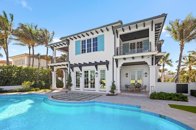 back of property with a balcony, fence, french doors, a patio area, and stucco siding