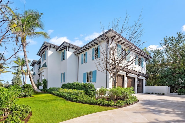 view of front facade with a front lawn, driveway, an attached garage, and stucco siding