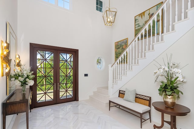 foyer entrance featuring stairs, french doors, a towering ceiling, and baseboards