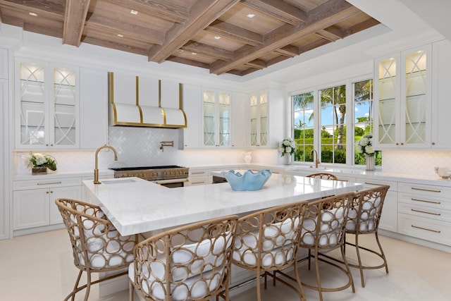 kitchen with coffered ceiling, a sink, and a kitchen bar