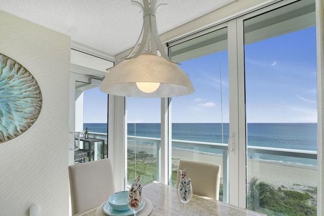 dining room with a textured ceiling, a beach view, and a water view