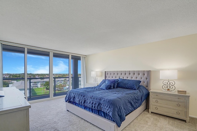 bedroom with carpet floors, access to exterior, floor to ceiling windows, and a textured ceiling