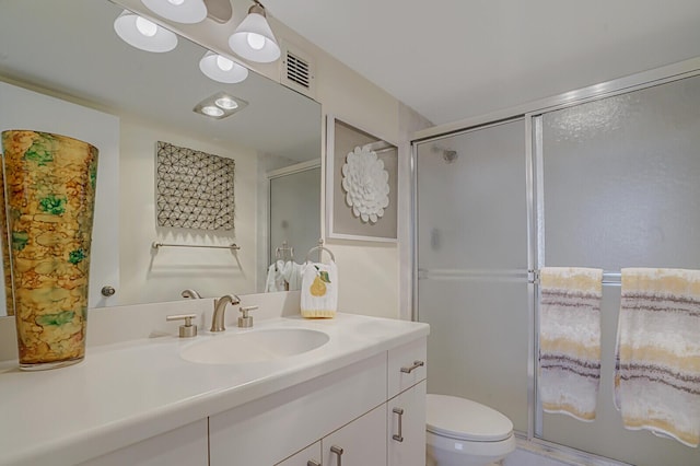 bathroom with toilet, a shower stall, visible vents, and vanity