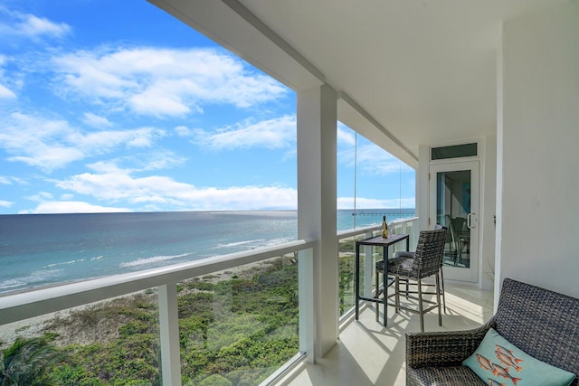 balcony featuring a view of the beach and a water view