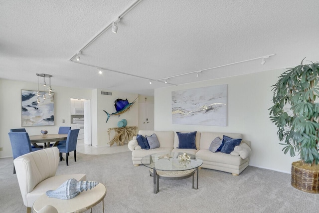 carpeted living room with visible vents, a textured ceiling, and track lighting