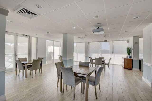 dining space with expansive windows, light wood finished floors, and visible vents