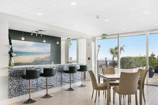 dining room featuring expansive windows, a drop ceiling, wood finished floors, and rail lighting