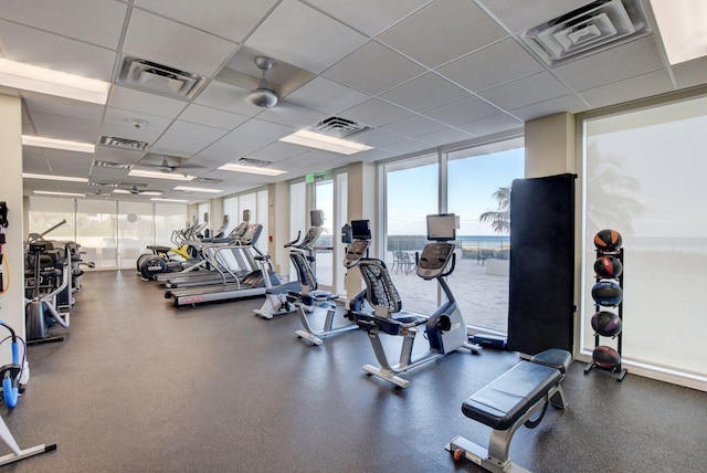 gym featuring expansive windows, a paneled ceiling, and visible vents