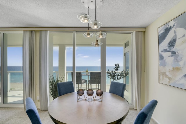 dining area featuring a wall of windows, carpet flooring, a water view, and a textured ceiling