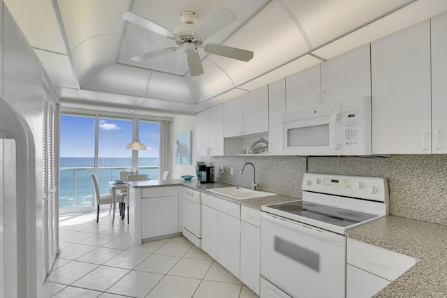 kitchen featuring white appliances, decorative backsplash, a sink, and a raised ceiling