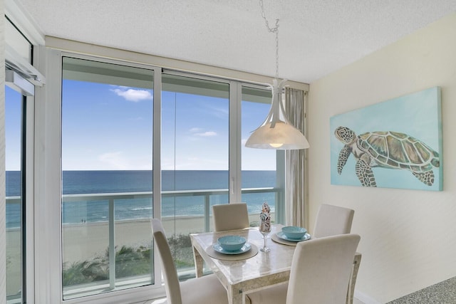 dining space featuring a textured ceiling, a beach view, and a water view