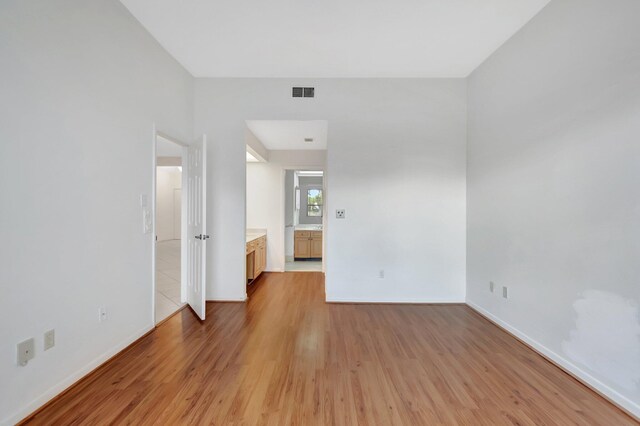 empty room featuring light wood-style floors, visible vents, and baseboards