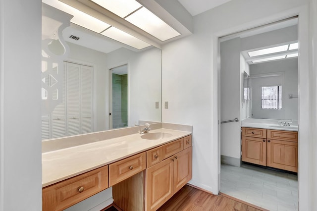 bathroom featuring baseboards, visible vents, wood finished floors, and vanity